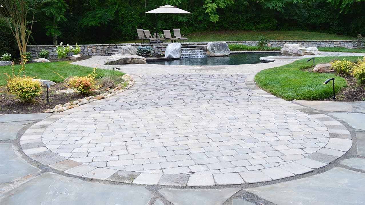 Paver patio installation beside a backyard pool deck